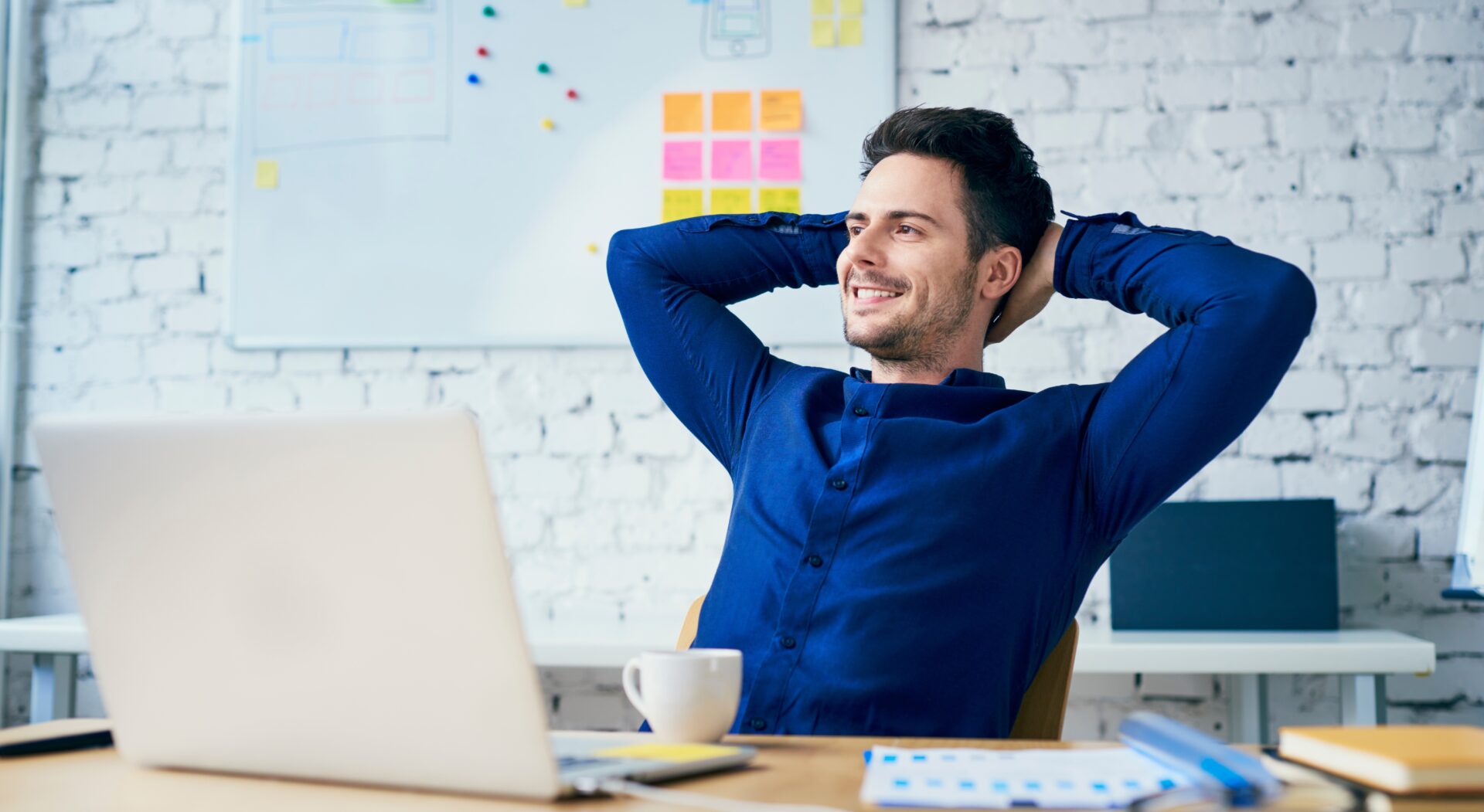 Satisfied young man in office looking away